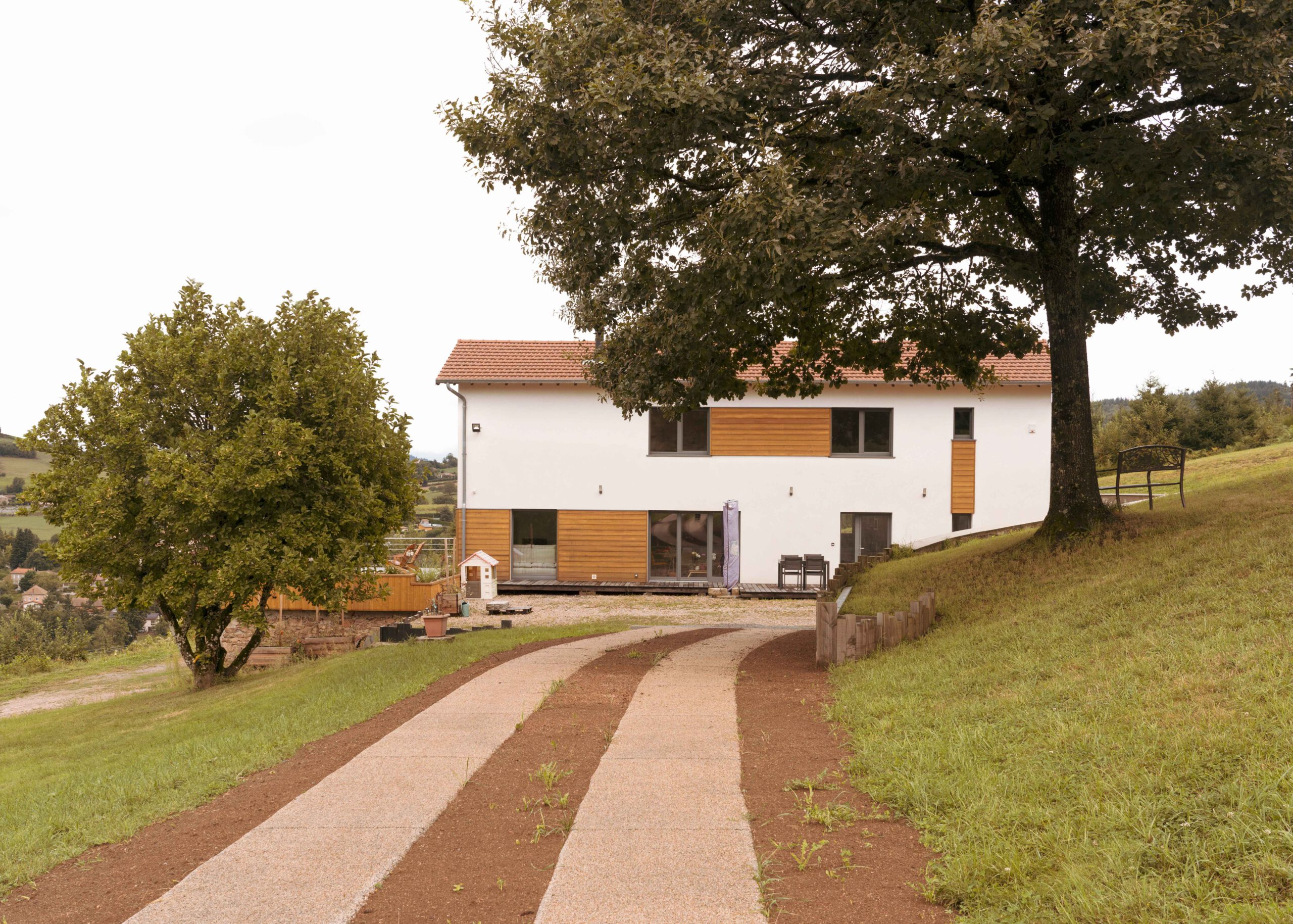 Photographie d'une maison du Roannais restructurée par un architecte en rénovation de maison. Celle-ci a un rendu moderne, tout en blanc et bois.