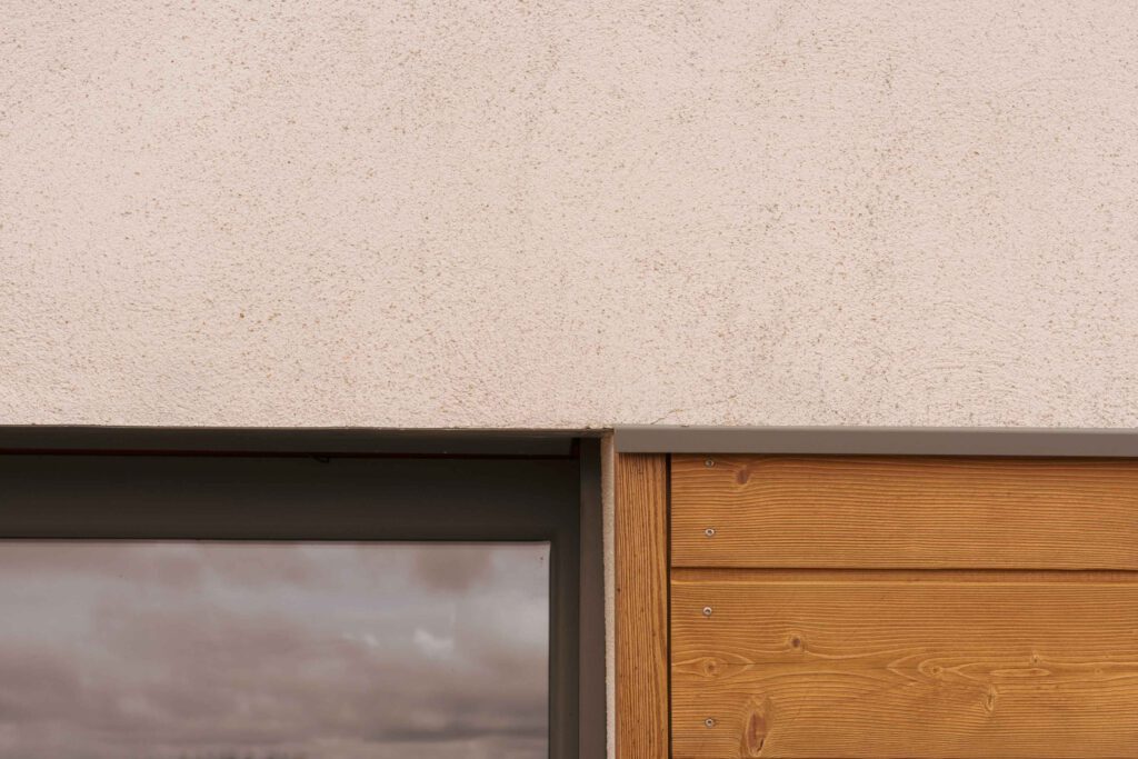 Photographie du détail d'une maison après sa restructuration avec des bardages en bois.