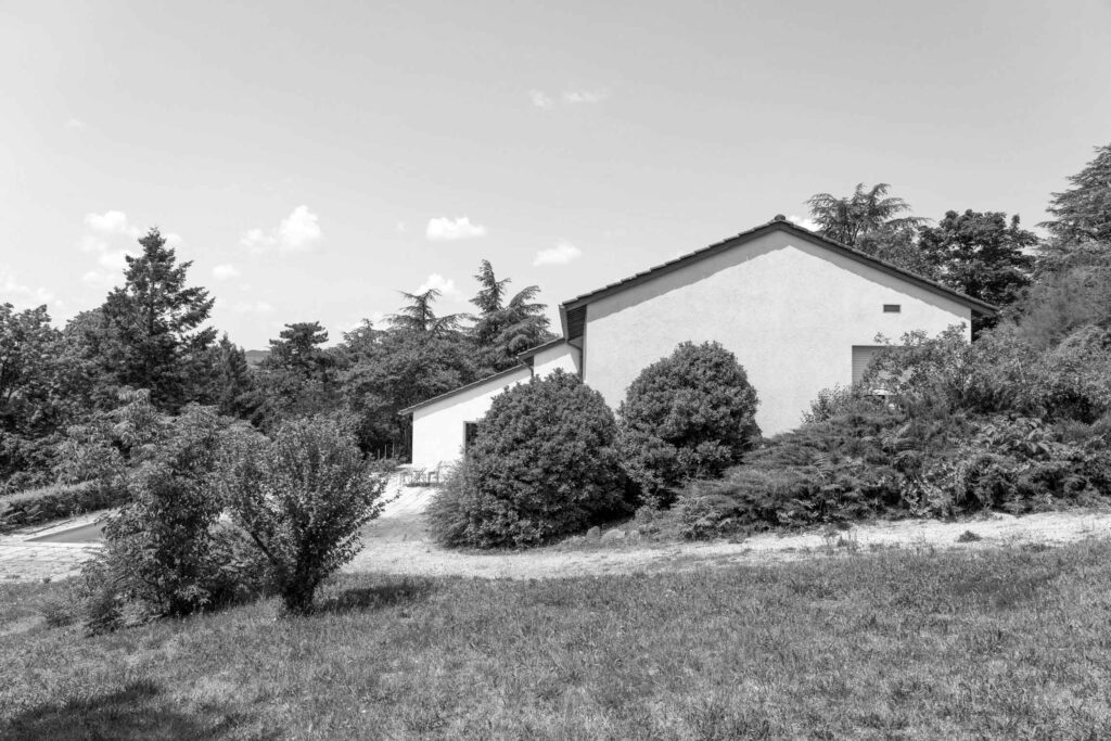 Photographie en noir et blanc d'une maison des années 70 avant rénovation. Vue de l'extérieur.