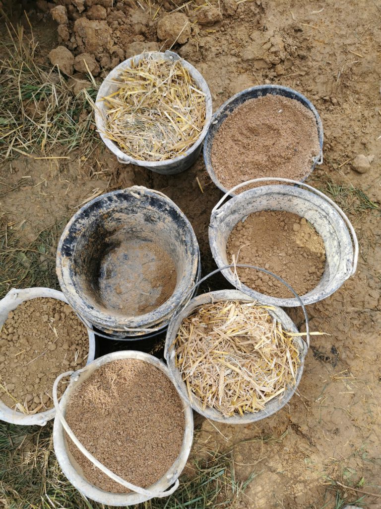 Photographie de pots remplis d'enduite terre et de paille pour l'isolation d'une maison dans l'Ain.