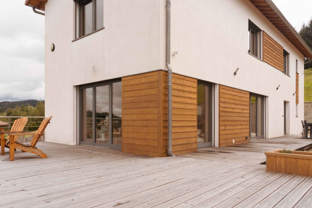 Photographie de l'extérieur d'une maison après sa restructuration avec des bardages en bois, près de Roanne.